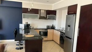 Uma cozinha moderna com uma ilha central, eletrodomésticos de aço inoxidável e armários de cor escura.