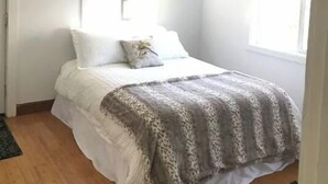 Een slaapkamer met een bed, een raam en een deur.