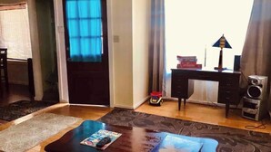 Een kamer met een bureau, een stoel, een klein tafeltje met een tijdschrift, een autootje en een speaker.