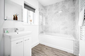 Ein modernes Badezimmer mit einem weißen Waschtisch, einer großen Badewanne und einer Duschkabine.