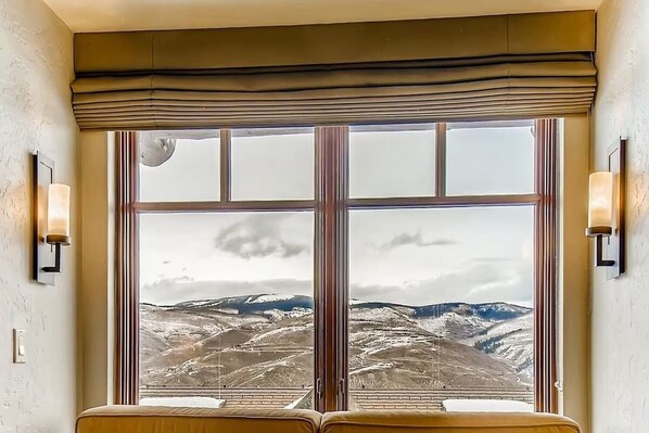 A room with a large window offering a view of a mountainous landscape.