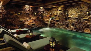 A spa area with a stone wall, a small waterfall, and lounge chairs with lanterns. - Beaver Creek Luxury 2BR, 2Bath ski-in & ski-out suite inside the Ritz-Carlton (Beaver Creek)
