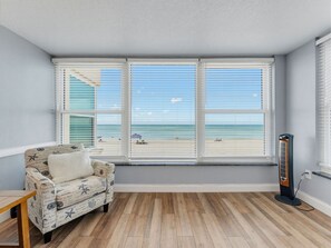 A room with a beach view, a patterned sofa, and a standing heater.