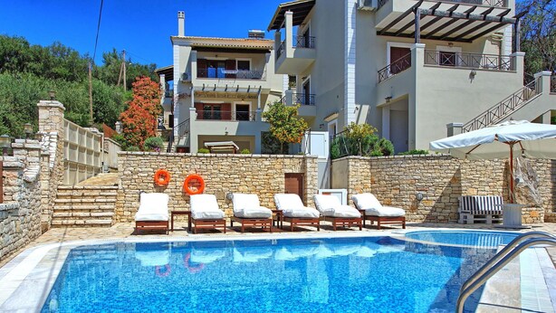 Una piscina con sillas de descanso y un muro de piedra.