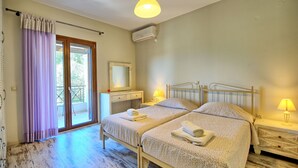 Un dormitorio con dos camas, un balcón, un espejo, una mesita de noche con lámpara y un equipo de aire acondicionado.