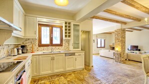 Una cocina amplia con una isla grande, vigas de madera y suelo de piedra.
