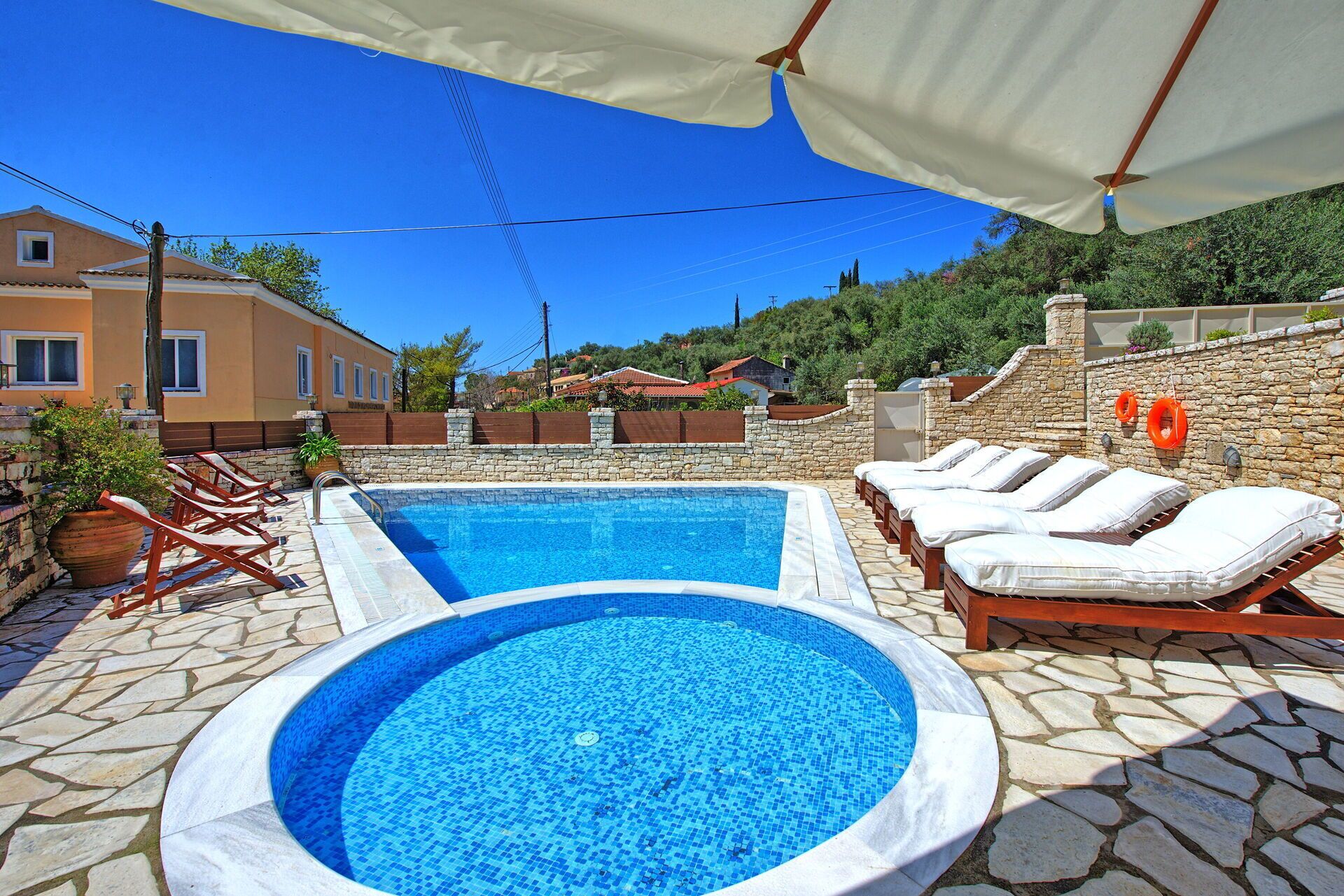 Une piscine avec des chaises longues et un mur en pierre.