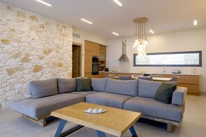 Relax in this stylish living room with a large L-shaped sofa, wooden coffee table, and pendant light.