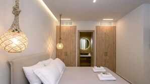 A bedroom with a bed, pillows, a hanging light fixture, and a wooden wardrobe with a mirror.