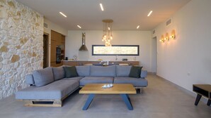 A modern living room with a grey sectional sofa, a wooden coffee table, and a stone wall.