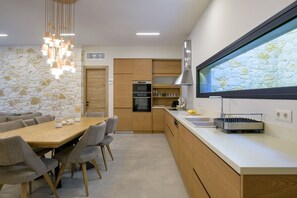 Una cocina moderna con pared de piedra, armarios de madera y un comedor con mesa y sillas.