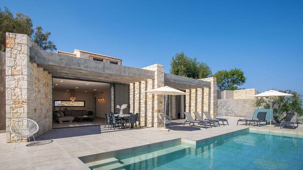 A modern house with a swimming pool, stone walls, and outdoor seating.