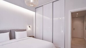 Et moderne soveværelse med en stor seng, et garderobeskab og et walk-in closet.
