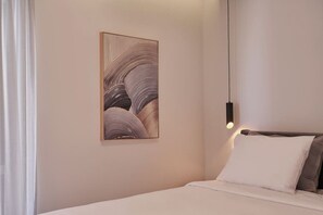 A hotel room with a bed, a wall-mounted artwork, and a hanging light fixture. - A Sunkissed retreat under the Acropolis (Athina)