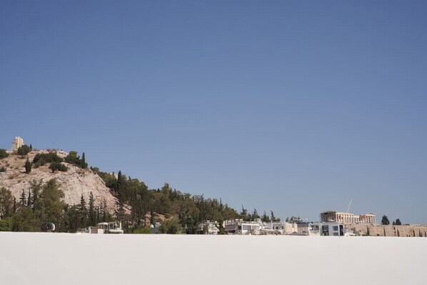 A coastal town with a prominent hill featuring ancient ruins. - A Sunkissed retreat under the Acropolis (Athina)