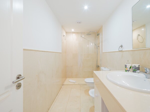 A modern bathroom with a shower, toilet, and sink.