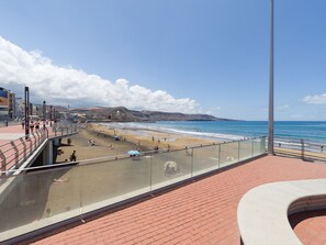 A beach with a glass railing, a brick walkway, and a view of the ocean.