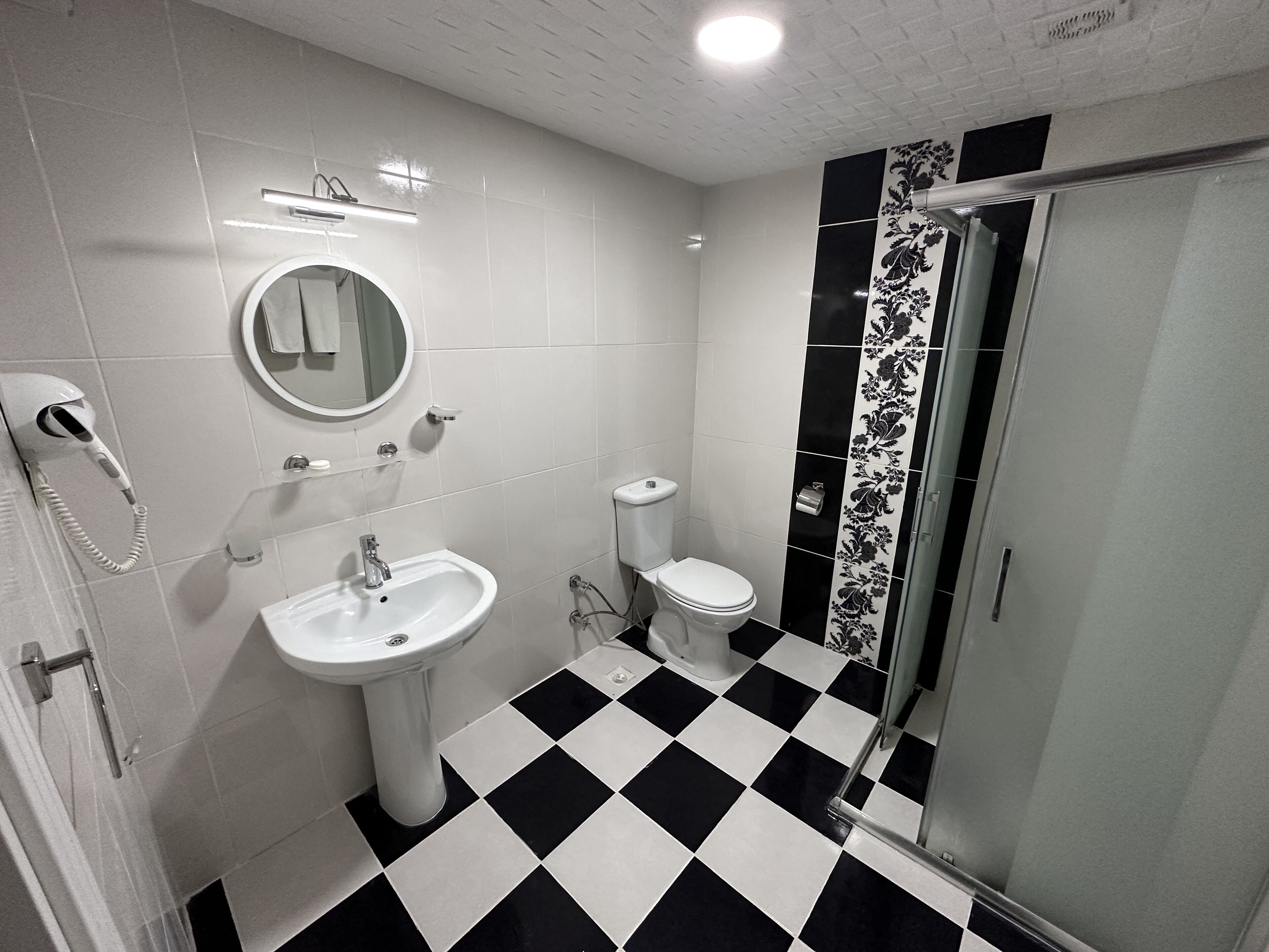 A bathroom with a white sink, toilet, and a shower area.