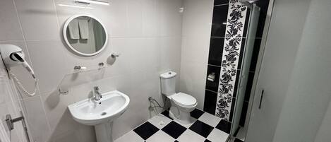 A bathroom with a white sink, toilet, and a shower area.
