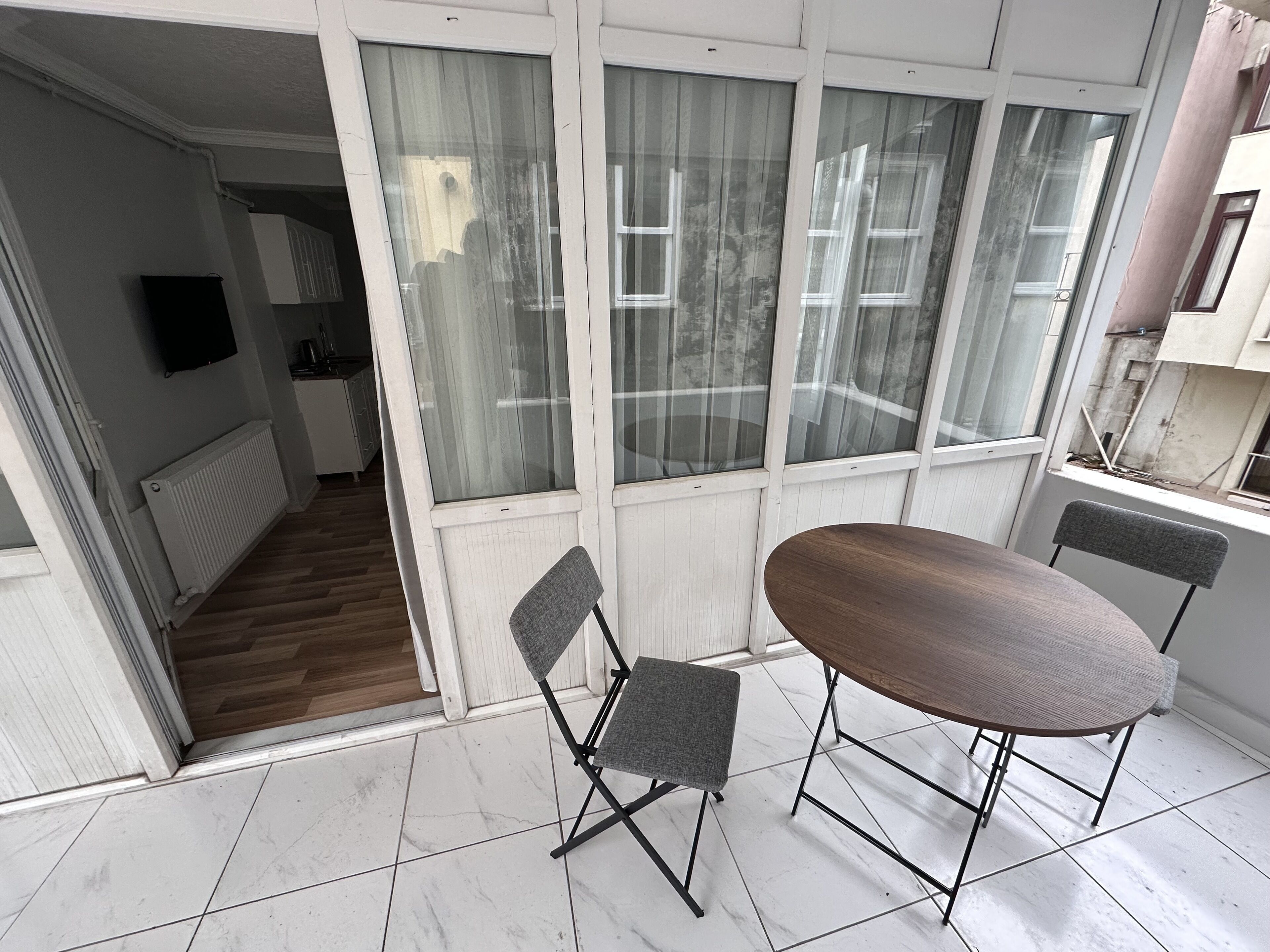 Een balkon met een eettafel en stoelen, uitzicht op de omgeving en een keuken in de achtergrond.