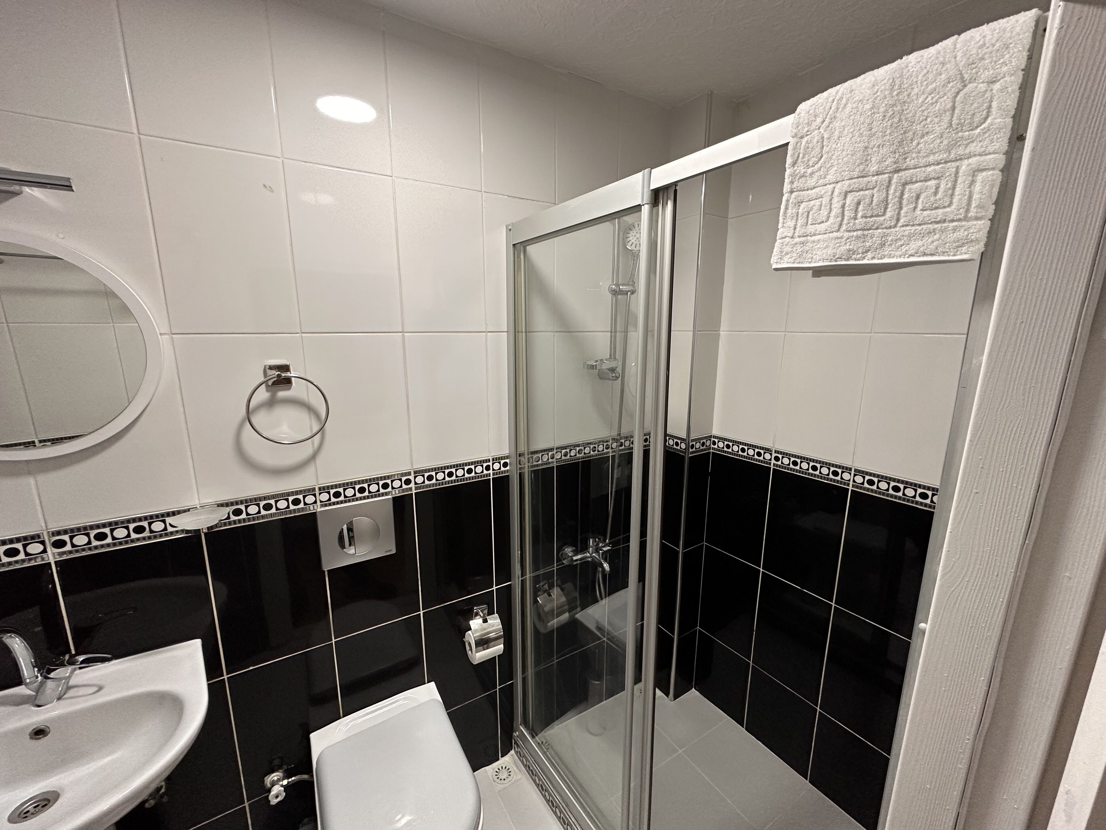 A bathroom with a sink, toilet, and glass shower enclosure.