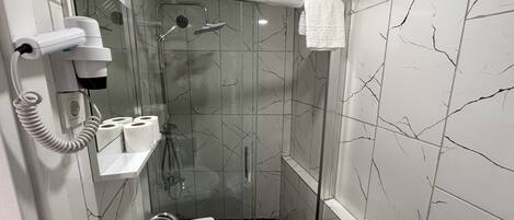 A modern bathroom with a glass-enclosed shower, a white sink, and a towel rack.