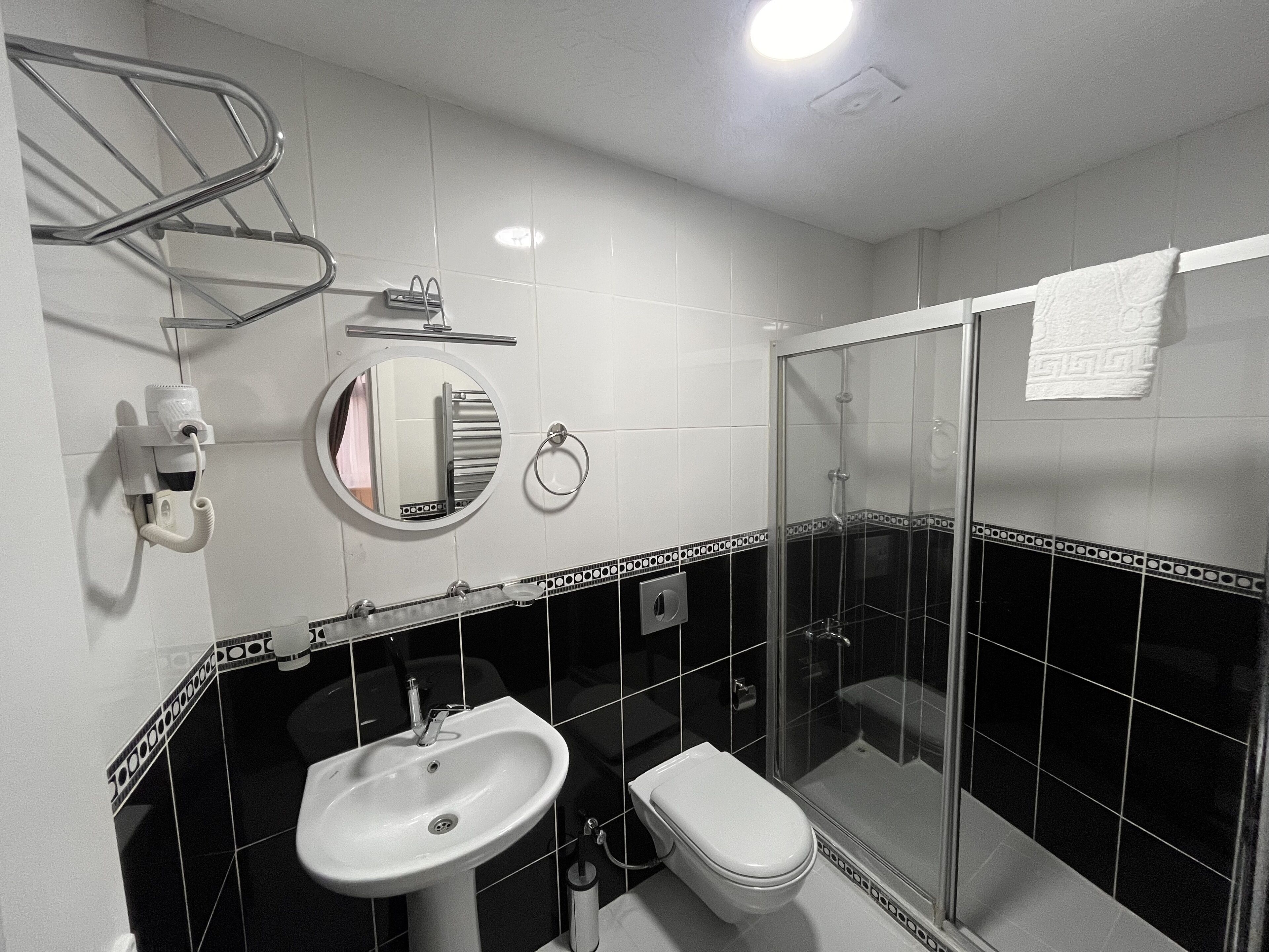 Un baño con lavamanos, inodoro y ducha con mampara de vidrio.