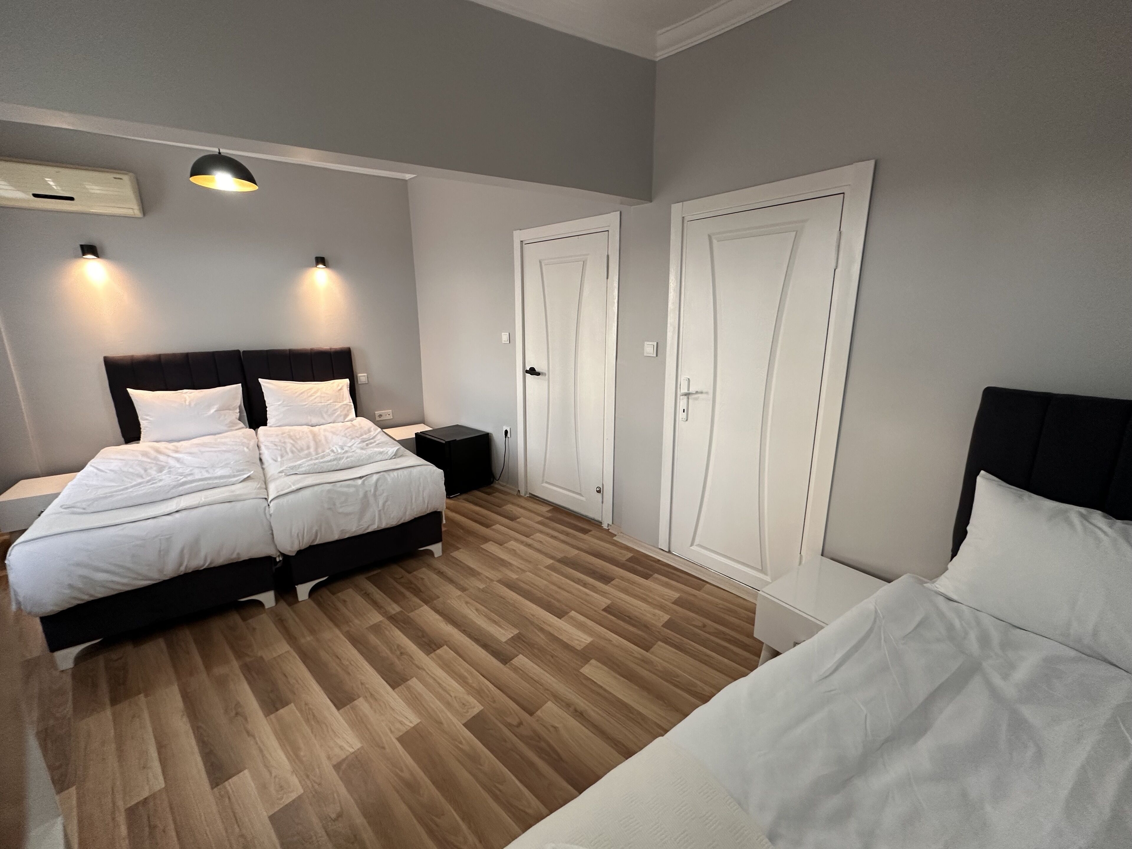 Un dormitorio con cama, mesitas de noche, armario y lámpara en el techo.
