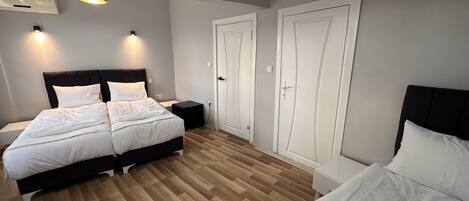 Un dormitorio con cama, mesitas de noche, armario y lámpara en el techo.
