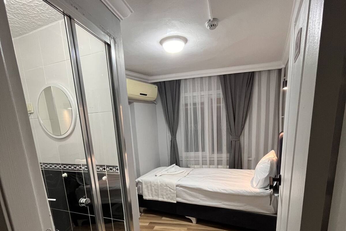 A bedroom with a sliding glass door, a bed, a bedside table, and a mirror.