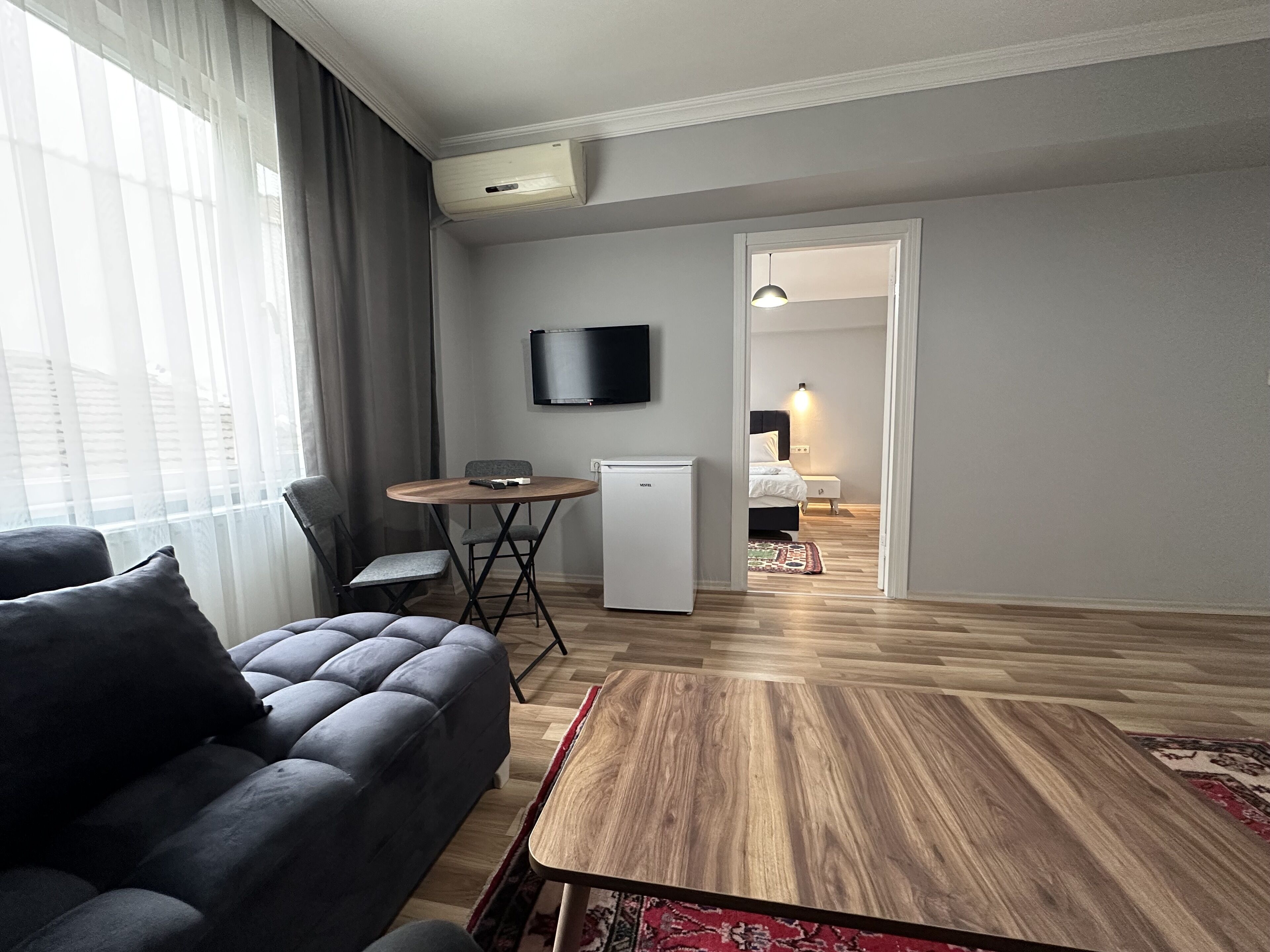 Una sala de estar moderna con un sofá, una mesita y un televisor montado en la pared.