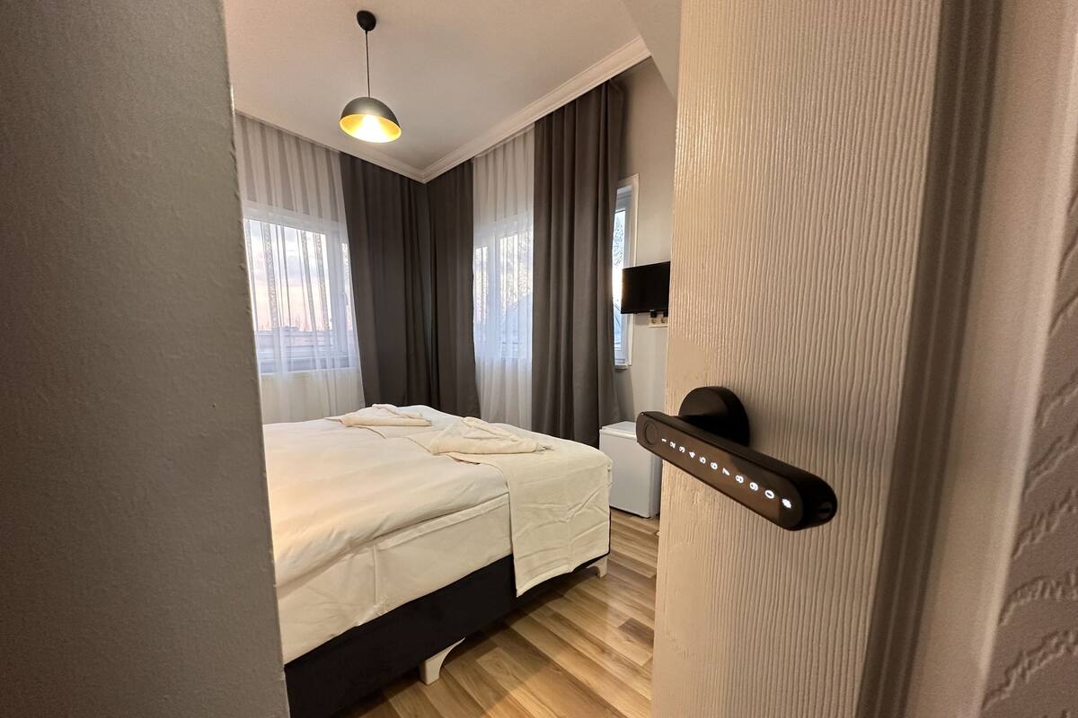 A modern hotel room with a bed, a desk, and a television.
