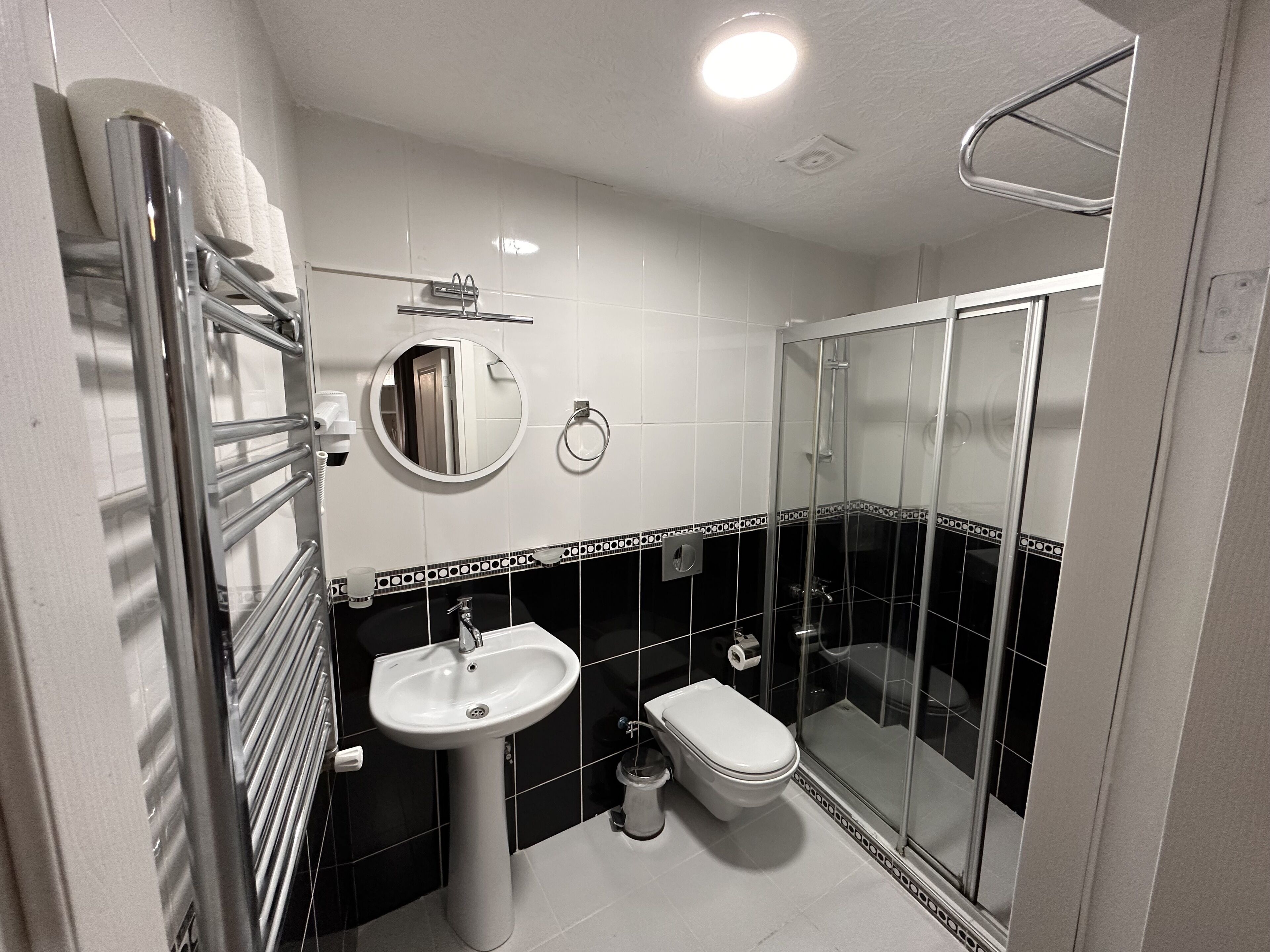 Un baño moderno con cabina de ducha de vidrio, lavamanos pedestal y un inodoro.