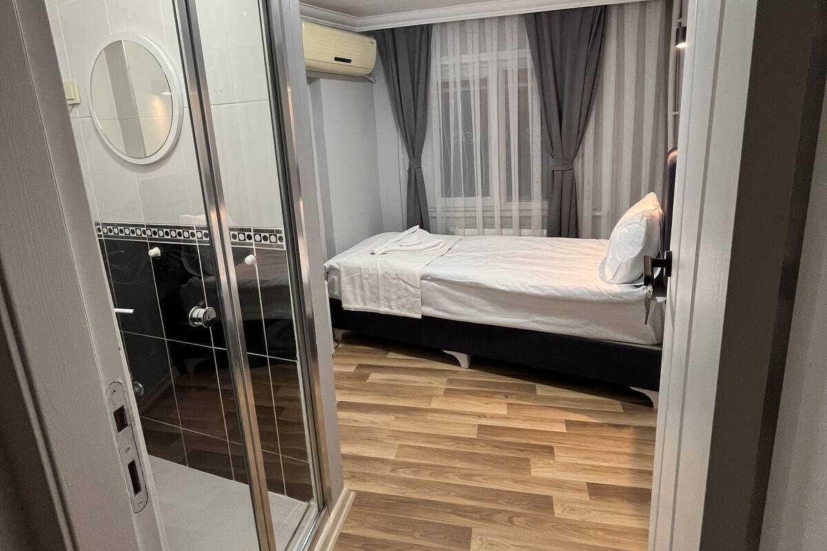 A bedroom with a bed, a sliding glass door, a mirror, and a ceiling light.