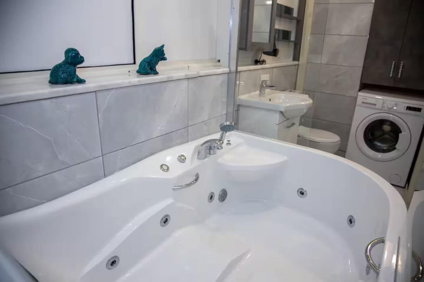 Une salle de bain moderne avec une grande baignoire, un lavabo et un lave-linge.