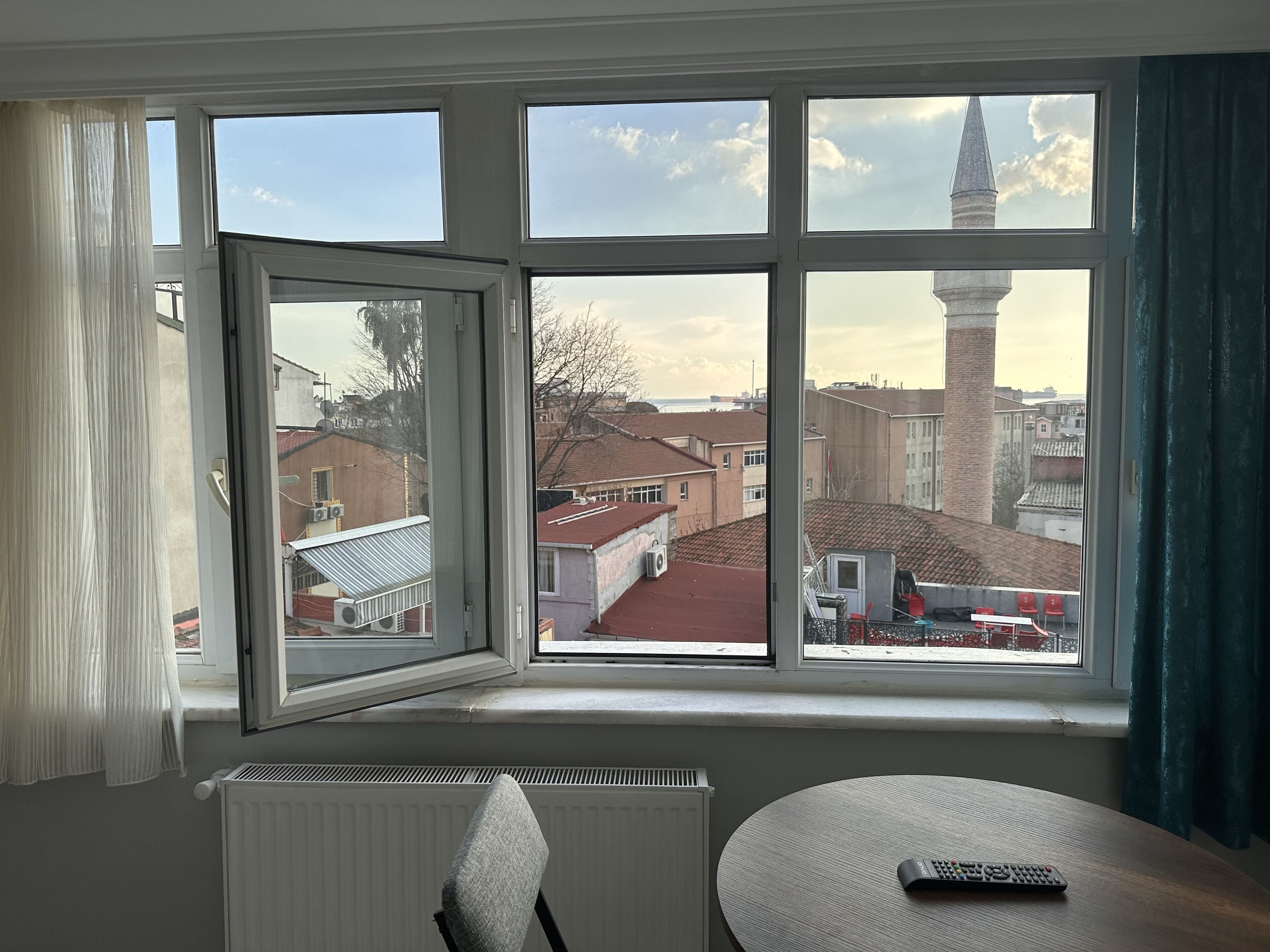 A room with a large window overlooking a cityscape, including a church spire.