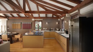 A spacious kitchen with wooden beams, a central island, and modern appliances. - Villa Famoso with Pool (Rovinj)