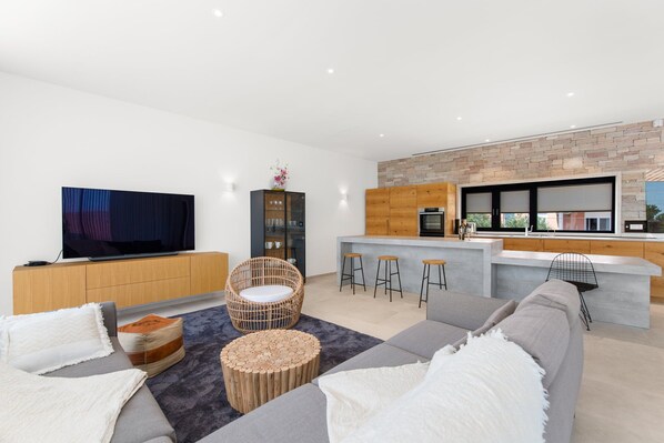 Un salon moderne avec un téléviseur à écran plat, un canapé, un fauteuil en osier et une table basse.