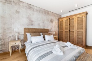 Une chambre à coucher avec un grand lit, une armoire en bois et une table de chevet avec des lampes.