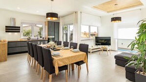 A modern kitchen with a dining area, a TV, and a pool view. - Villa Lotus with Heated Pool (Pula)