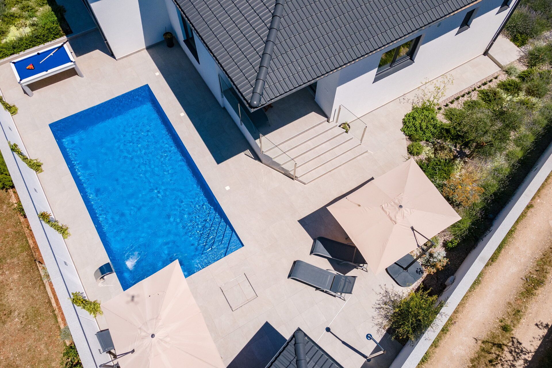 Vue aérienne d’une propriété résidentielle dotée d’une piscine, d’un espace salon extérieur et d’un patio couvert.