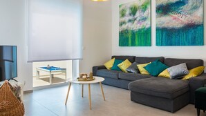 A modern living room with a grey sofa, yellow and green cushions, a round white coffee table, and abstract paintings on the wall. - Villa Lotus with Heated Pool (Pula)