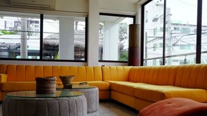 Een moderne woonkamer met een geel hoekbank, een glazen salontafel en een rode fauteuil.