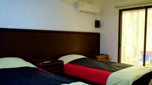 Een hotelkamer met twee bedden, een houten hoofdbord, een nachtkastje en een raam met gordijnen.