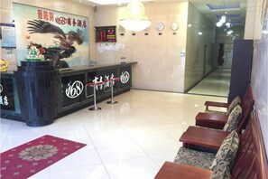 A hotel reception area with a black reception desk, a red carpet, and a seating area with wooden benches. - 168 Business Hotel (Jinjiang)