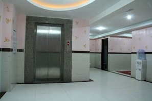 An elevator in a lobby with a water dispenser nearby. - 168 Business Hotel (Jinjiang)