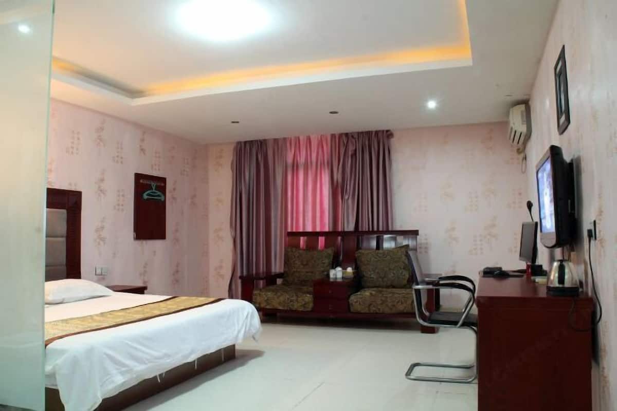 A hotel room with a bed, a sofa, a desk, and a TV.