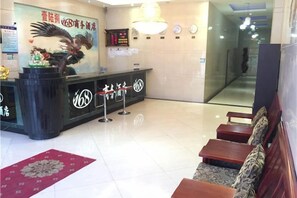 A hotel reception area with a black reception desk, a red carpet, and a seating area with wooden benches. - 168 Business Hotel (Jinjiang)