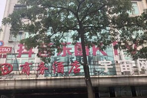 A building with a large sign in red characters, a tree in front, and a clear sky. - 168 Business Hotel (Jinjiang)