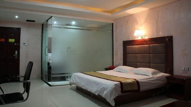 A bedroom with a bed, bedside table, and a glass shower enclosure. - 168 Business Hotel (Jinjiang)